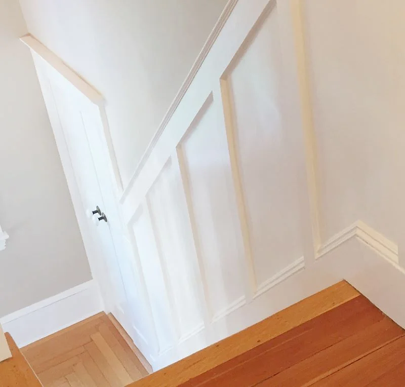 Stairway wainscoting painted white with top rails and base cap moulding.